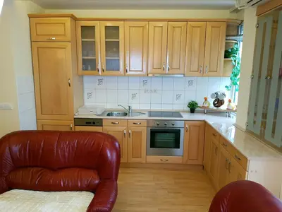 a kitchen with wooden cabinets and a leather couch at Apartman Harmony in Smederevo
