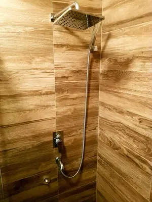 a shower with a shower head on a wooden wall at Apartman Harmony in Smederevo
