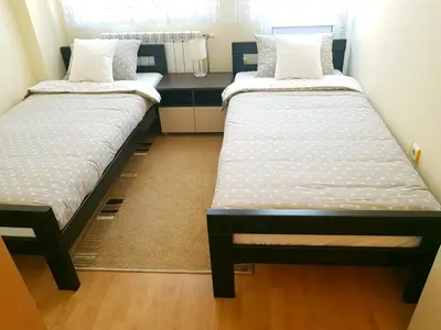 two twin beds in a room with a desk at Apartman Harmony in Smederevo