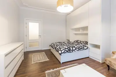 a white bedroom with a bed and a table at Belgrade Center Apartment Slavija Square II in Belgrade