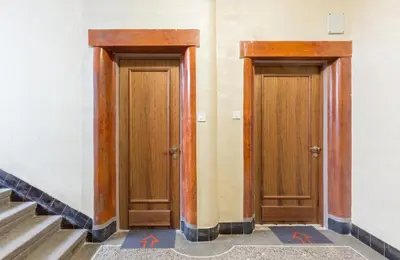 two wooden doors in a hallway with stairs at Belgrade Center Apartment Slavija Square II in Belgrade