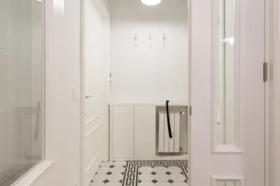 a white hallway with a black and white tile floor at Belgrade Center Apartment Slavija Square II in Belgrade