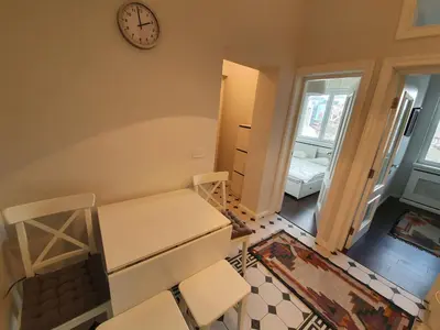 a room with a table and chairs and a clock at Belgrade Center Apartment Slavija Square III in Belgrade