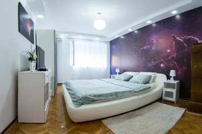 a bedroom with a large white bed with a purple wall at White Night City Center Apartman in Belgrade