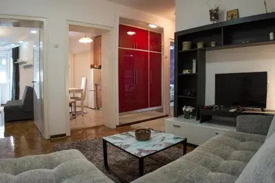 a living room with a couch and a red door at White Night City Center Apartman in Belgrade