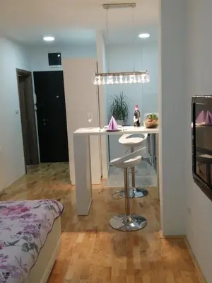 a kitchen and living room with a table and a bed at Apartman Lux in Nova Pazova