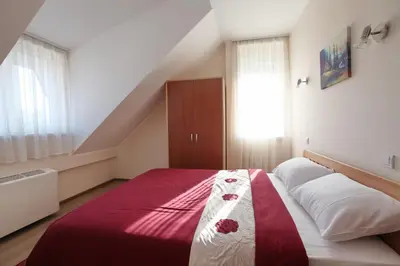 a bedroom with a bed with a red and white blanket at Hotel Novella Uno in Novi Banovci