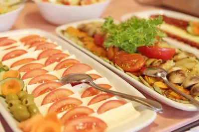 a table topped with three trays of food with spoons at Hotel Novella Uno in Novi Banovci