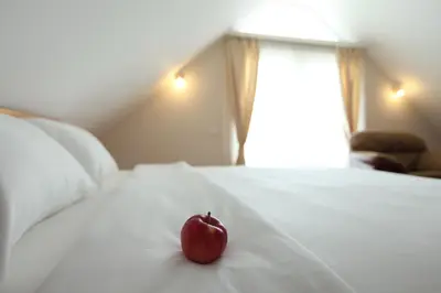 a red apple sitting on top of a white bed at Hotel Novella Uno in Novi Banovci
