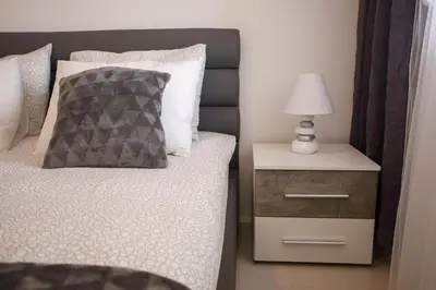 a bedroom with a bed and a nightstand with a lamp at Apartman Niki in Arandjelovac