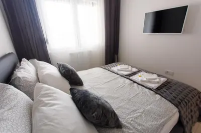 a bedroom with a bed with pillows and a television at Apartman Niki in Arandjelovac