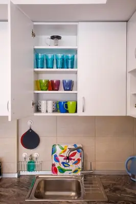 a kitchen with a sink and some bowls on shelves at Apartman Niki in Arandjelovac