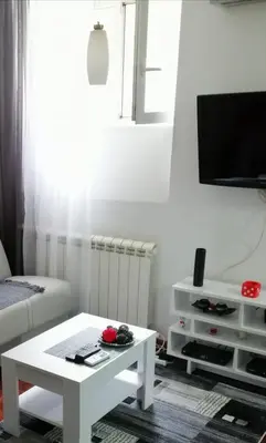 a living room with a white coffee table and a tv at Studio Apartman KOCKA in Belgrade
