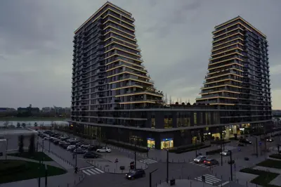 two tall buildings next to a parking lot with cars at Belgrade Waterfront Comfortable Apartment in Belgrade