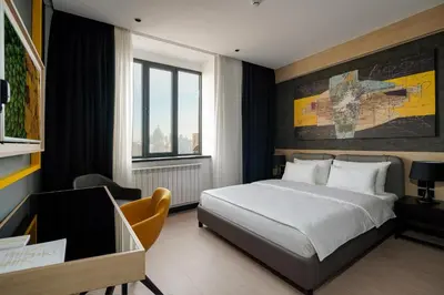 a bedroom with a bed and a desk and a window at Maccani Black Luxury Suites in Belgrade