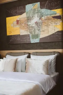 a bed with white pillows and a painting above it at Maccani Black Luxury Suites in Belgrade