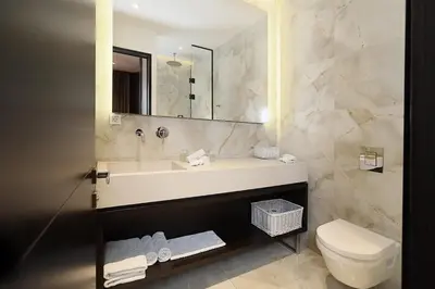 a bathroom with a sink and a toilet and a mirror at Maccani Black Luxury Suites in Belgrade