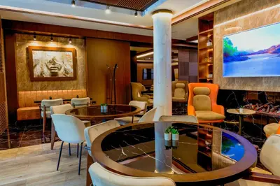 a lobby with tables and chairs and a flat screen tv at Nobel Gallery Hotel in Belgrade