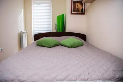 a bed with two green pillows on top of it at The Temple bells, flat in the heart of the city in Dušanovac (historical)