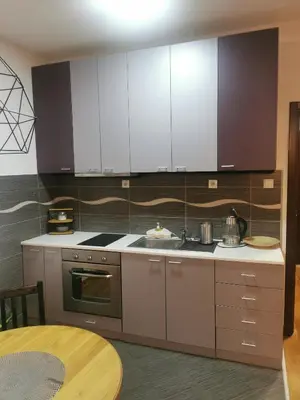 a kitchen with white cabinets and a wooden table at Charlie Aviv Park in Belgrade
