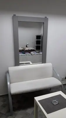 a living room with a white couch and a mirror at Apartman Pocerac in Belgrade