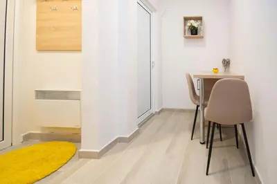 a room with a table and chairs and a yellow rug at Cvetni trg in Belgrade