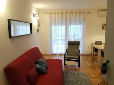 a living room with a red couch and a chair at Luka Lux apartman in Belgrade