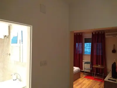 a bedroom with a bed and a bathroom with red curtains at Castel Bianco in Belgrade