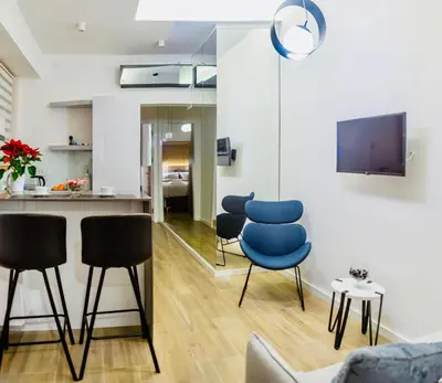 a living room with blue chairs and a kitchen at INNA Luxe & Wine- Central Belgrade Apartments in Belgrade
