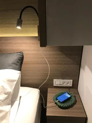 a bed with a night stand with a phone on it at INNA Luxe & Wine- Central Belgrade Apartments in Belgrade