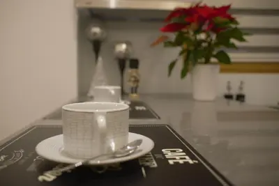 a white coffee cup and spoon on a table at INNA Luxe & Wine- Central Belgrade Apartments in Belgrade