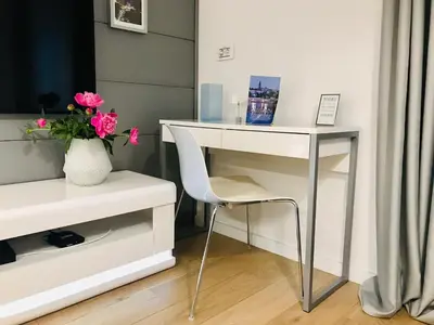 a white desk with a chair and a vase with pink flowers at SLAVNA - Luxe & Wine by the Fortress in Belgrade