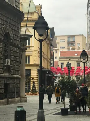 a group of people walking down a street with red umbrellas at SLAVNA - Luxe & Wine by the Fortress in Belgrade