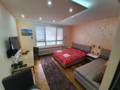 a bedroom with a bed and a couch and a window at Apartman DoDoLu in Belgrade