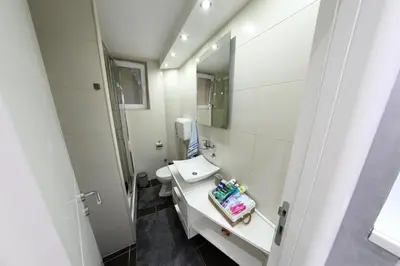 a white bathroom with a sink and a mirror at Apartment 