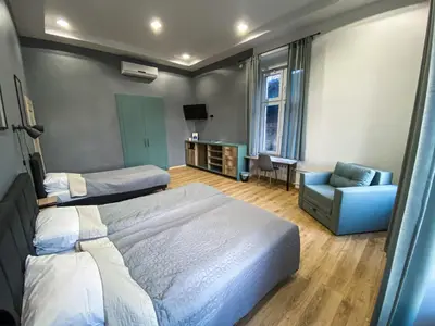 a bedroom with two beds and a couch and a chair at K43 Rooms in Belgrade