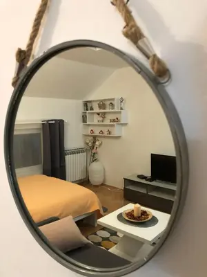 a mirror reflecting a bedroom with a bed and a table at Apartman Ana in Dušanovac (historical)