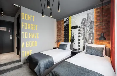 two beds in a room with a wall with a poster at 7 Rooms Suites in Belgrade