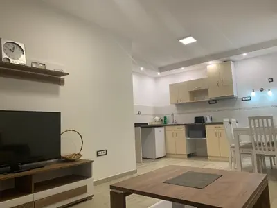 a living room with a tv and a table and a kitchen at MM Apartmani in Belgrade