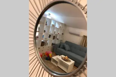 a mirror reflecting a living room with a blue couch at Apartman Iva in Belgrade