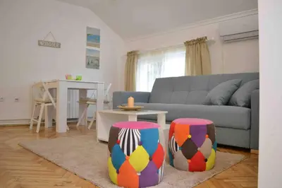 a living room with a couch and two colorful stools at Apartman Iva in Belgrade