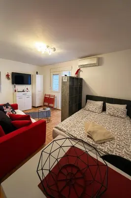 a bedroom with a bed and a red couch at Studio IKA Belgrade Airport Free Parking possible Self Check-In Terrace in Ledine
