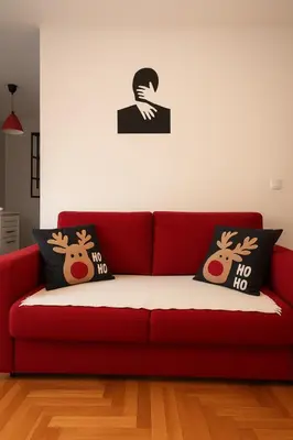 a red couch with two reindeer pillows on it at Studio IKA Belgrade Airport Free Parking possible Self Check-In Terrace in Ledine