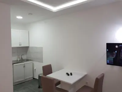 a white kitchen with a white table and chairs at Apartman Viktor in Belgrade