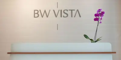 a vase with a purple flower in front of a sign at MVP apartment - Belgrade Waterfront in Belgrade