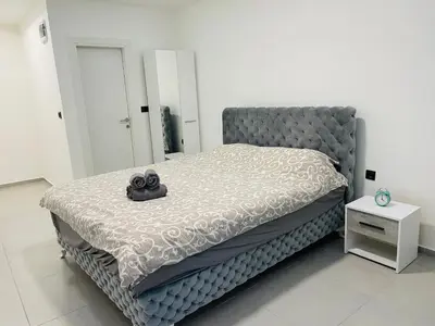 a bedroom with a large bed with a gray headboard at Luxury Centar in Arandjelovac