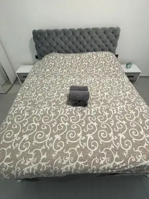 a bed with a black and white comforter on it at Luxury Centar in Arandjelovac