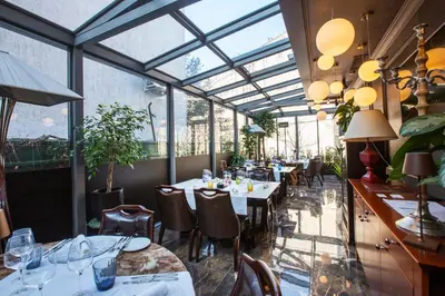 a restaurant with tables and chairs and glass ceilings at Eclat Luxury Hotel in Belgrade