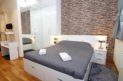 a bedroom with a large bed and a brick wall at Beograd Promenada Waterfront in Belgrade
