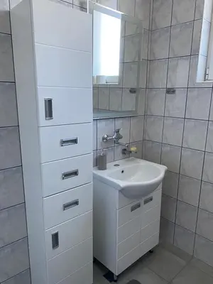 a white bathroom with a sink and a mirror at MAGIC M Apartment in Mali Mokri Lug